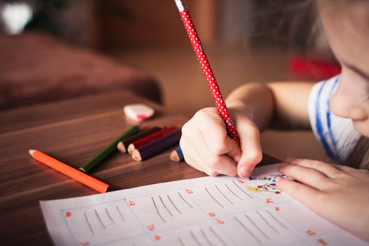dziewczynka pisze ołówkiem w podręczniku